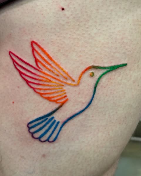 Hummingbird tattoo in rainbow linework on the ribs