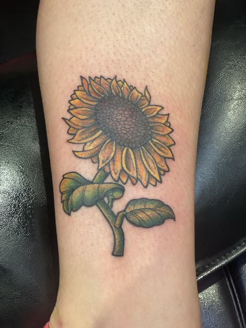 Sunflower tattoo in full color on a lower leg
