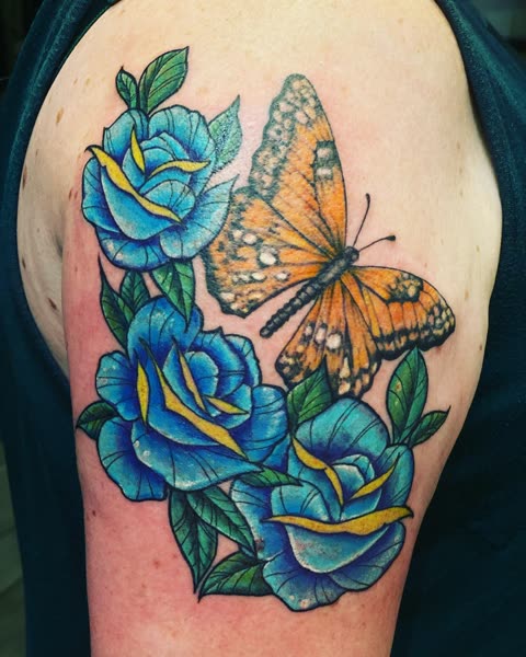 Blue roses tattoo with an orange butterfly, full color, on an upper arm
