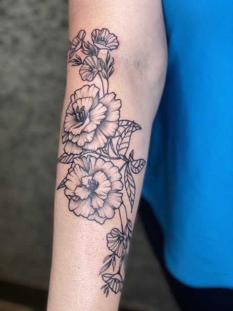 Fine line carnation tattoo with light stippling climbing a forearm