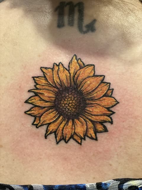 Sunflower tattoo in warm color on the upper back