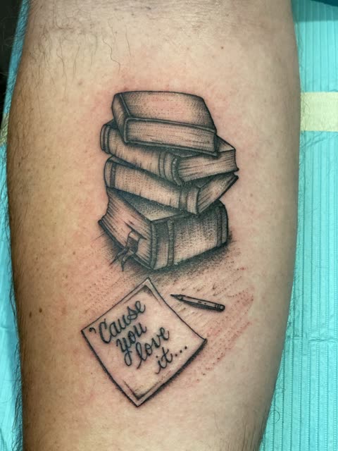Stack of books tattoo with a pencil and handwritten note, black shading, on a calf