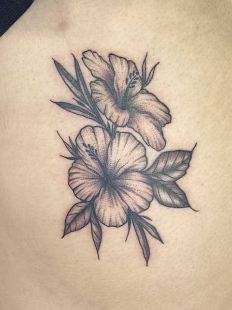 Hibiscus tattoo in black stipple shading on the ribs