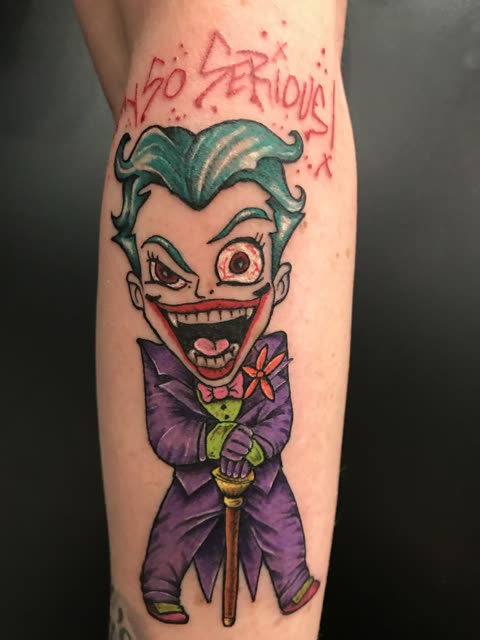 Cartoon Joker tattoo with So Serious in red script, full color, on a calf